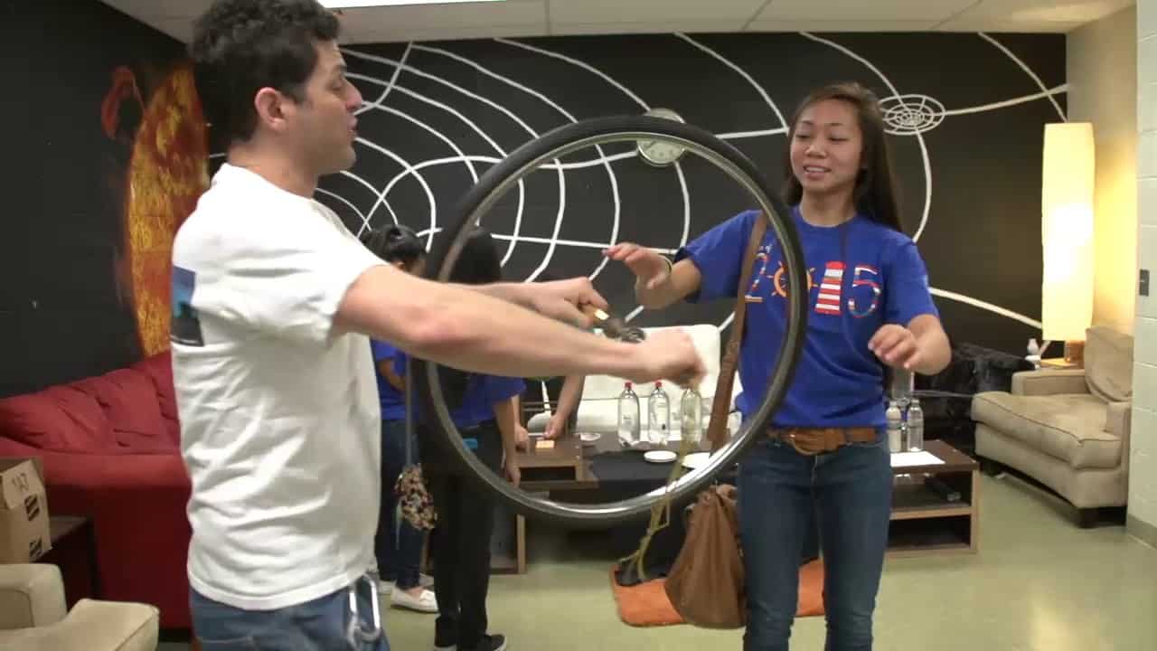 Instructor Nassir engages student in physics demonstration.